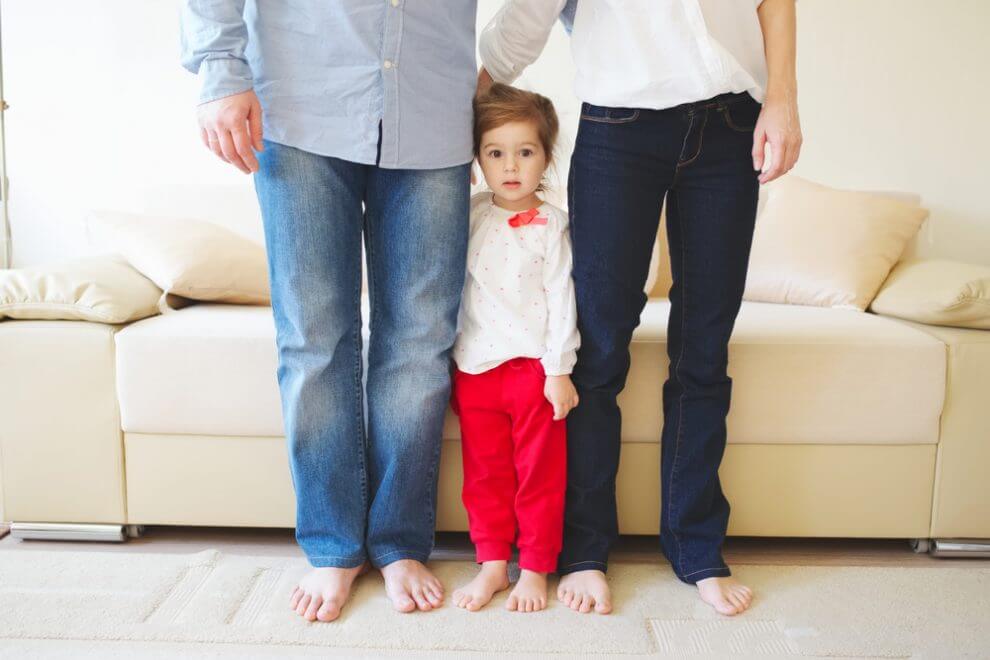A little girl standing in between her parents.